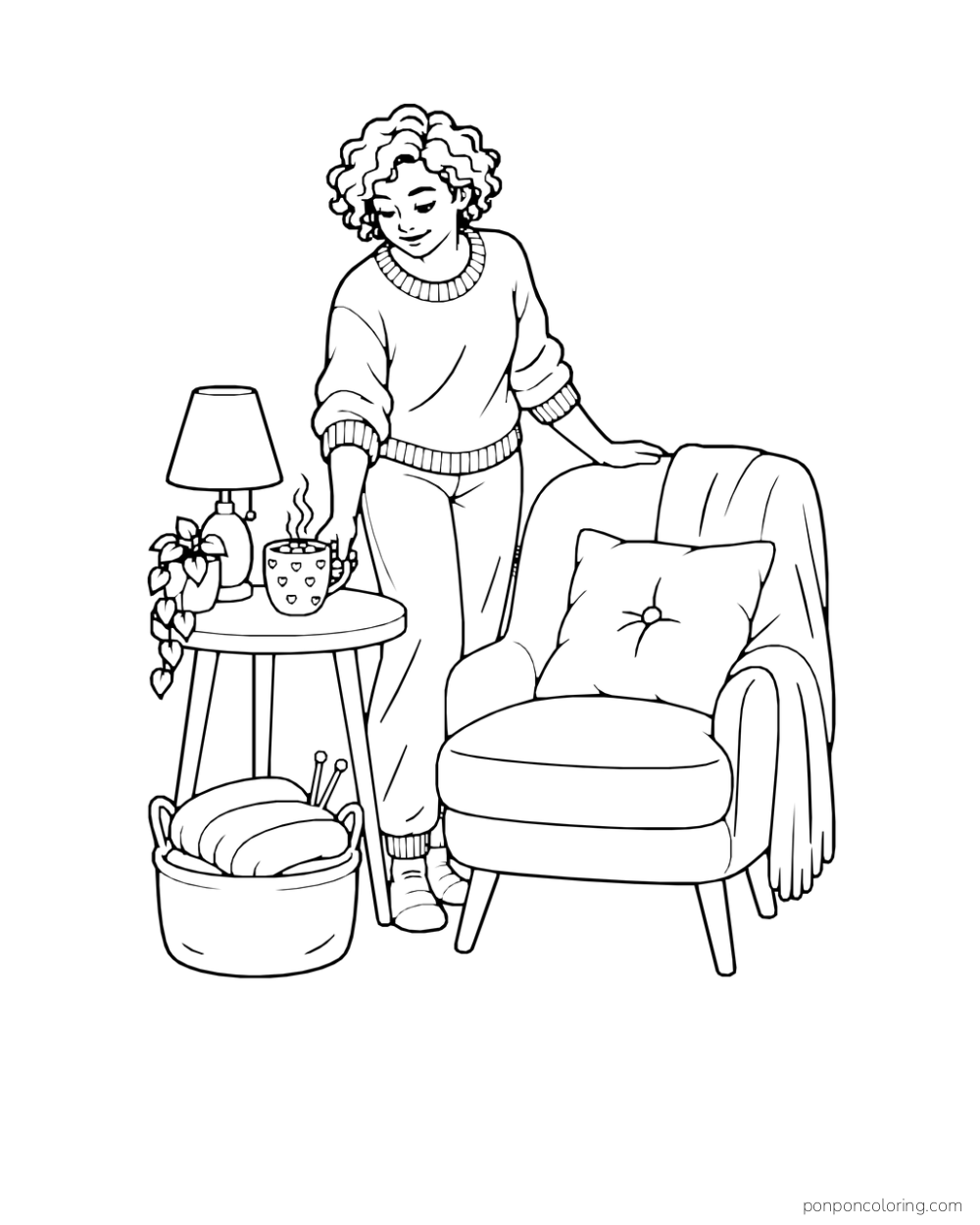 A person sets cocoa on a side table beside an armchair and a folded knitted piece.
