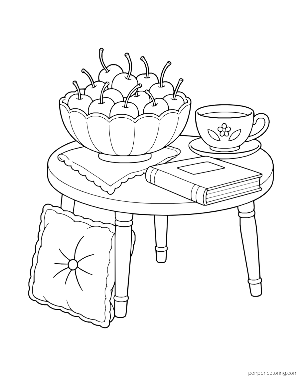 A scalloped bowl full of cherries on a cloth beside a flower-decorated teacup and a closed book, with a cushion against the round table.