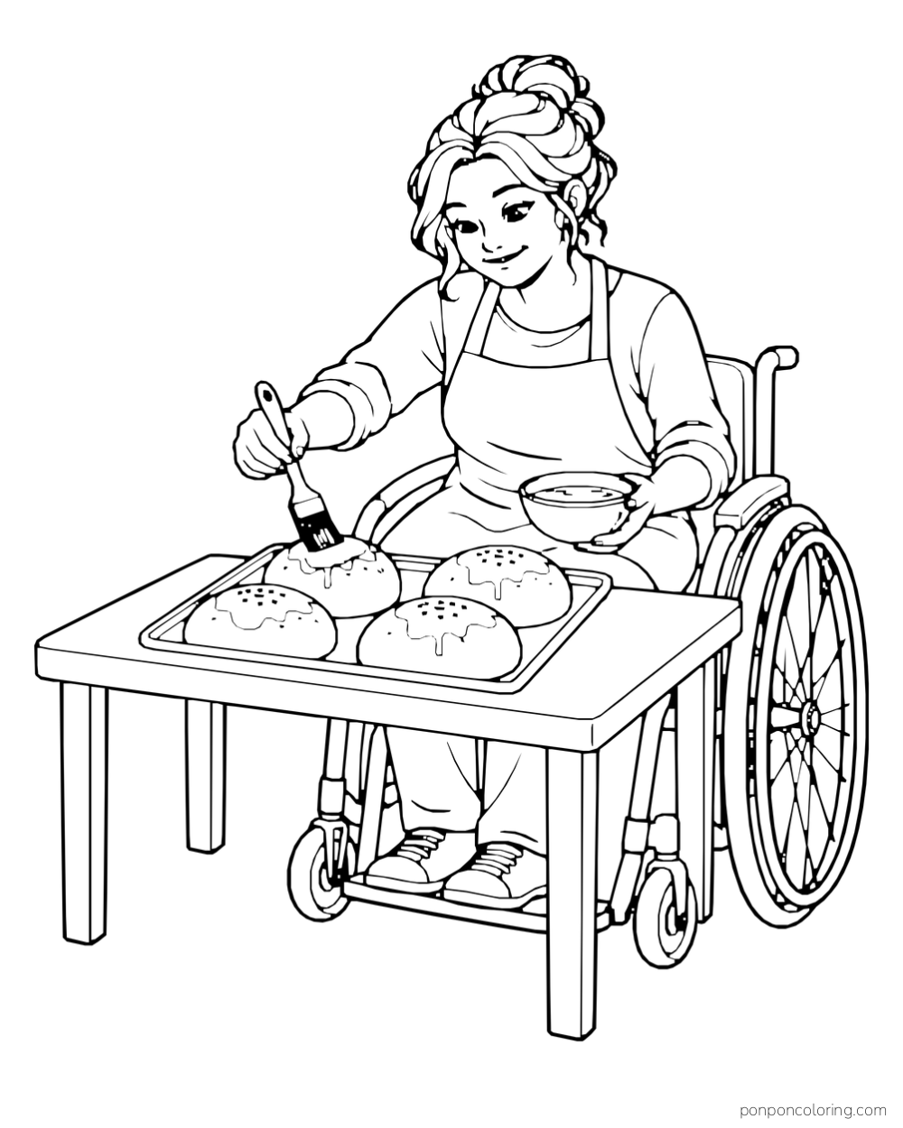 A wheelchair user brushes the tops of four bread rolls on a tray at a worktable.