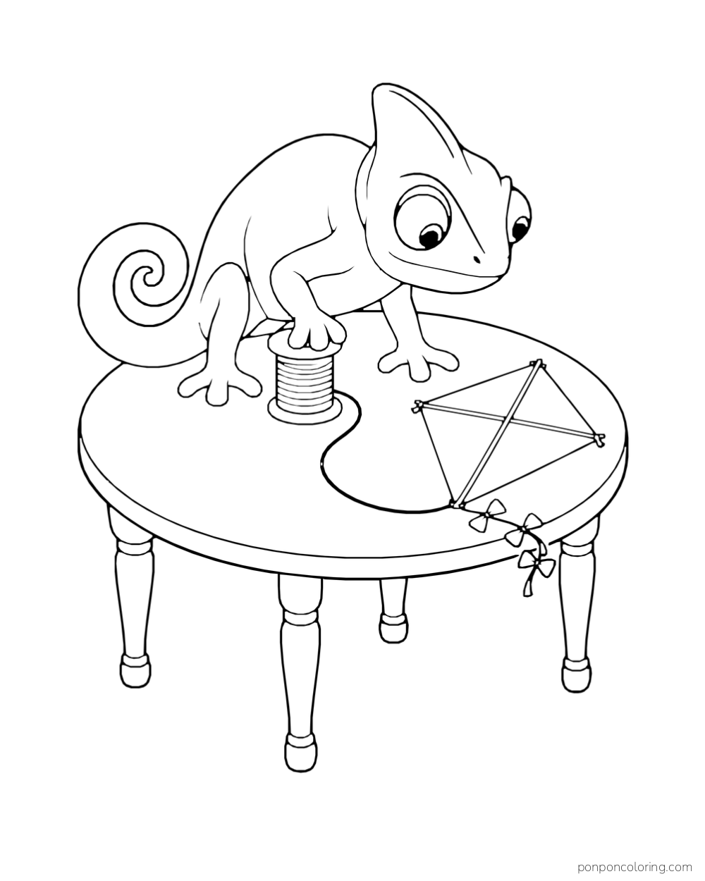 A chameleon rests one foot on a string spool beside a diamond paper kite on a round table.