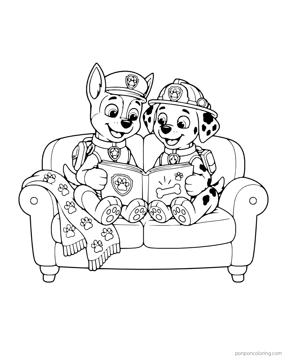 Chase and Marshall read a picture book on a sofa with a paw-print blanket.