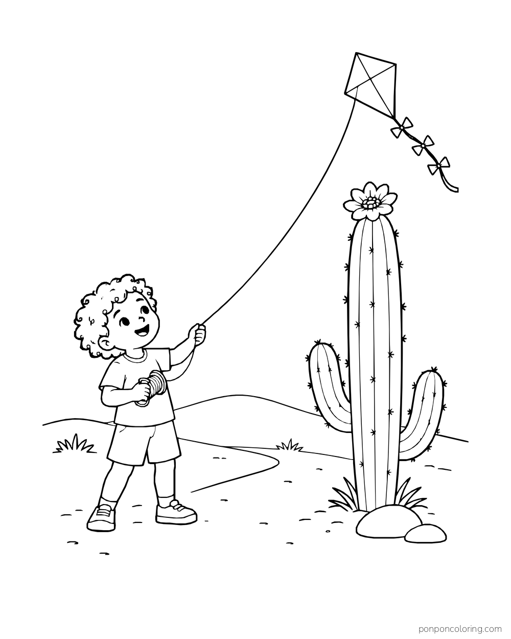 A child flies a diamond kite above a tall flowering cactus on a desert path.
