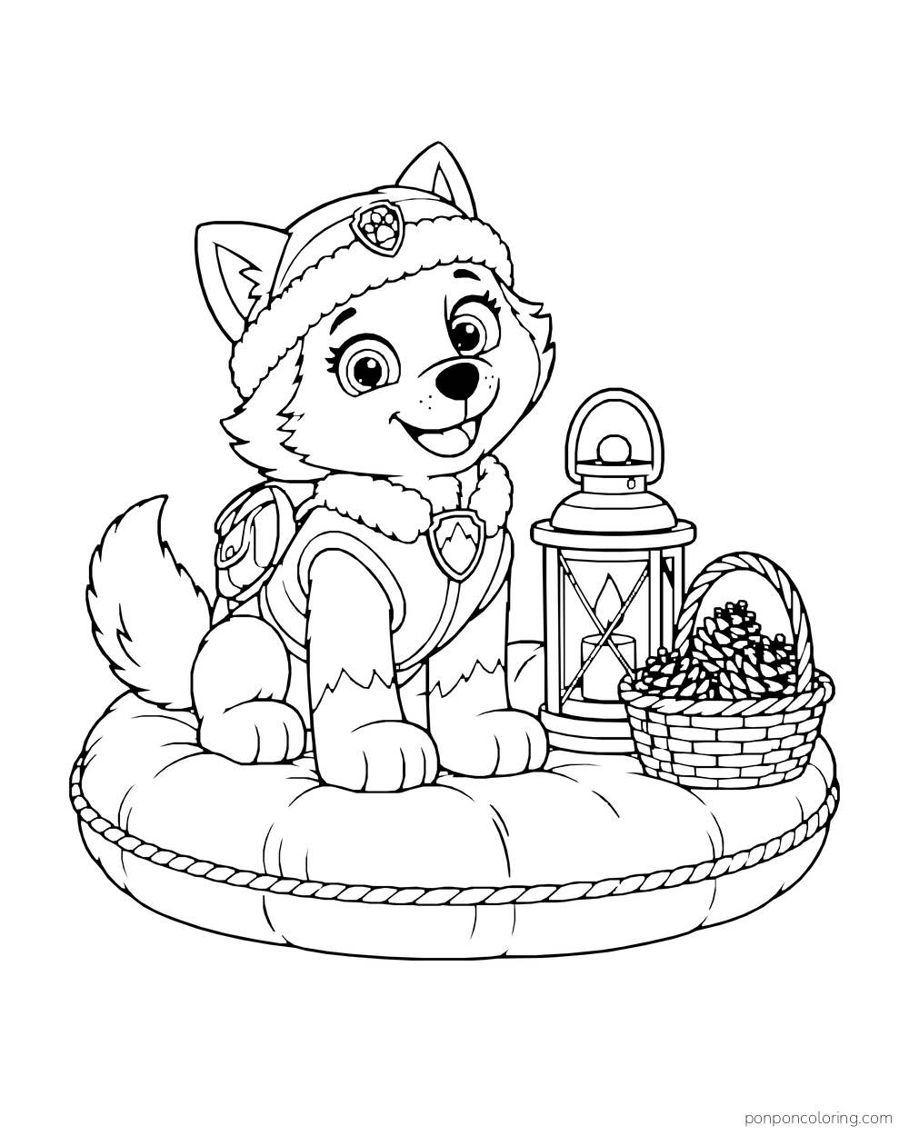 Everest sits on a round cushion beside a lantern and basket of pinecones.