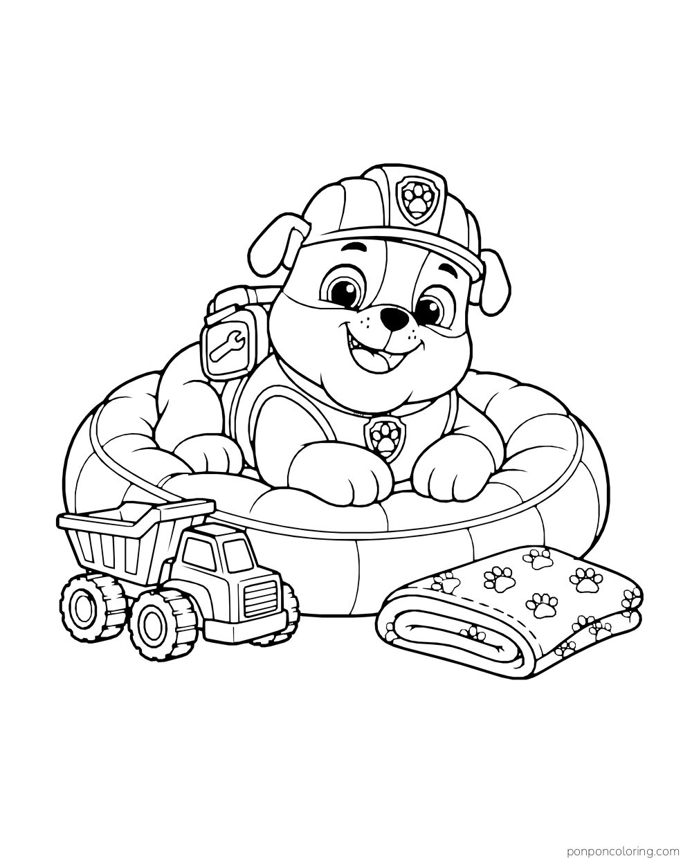 Rubble rests on a round cushion beside a toy dump truck and folded blanket.