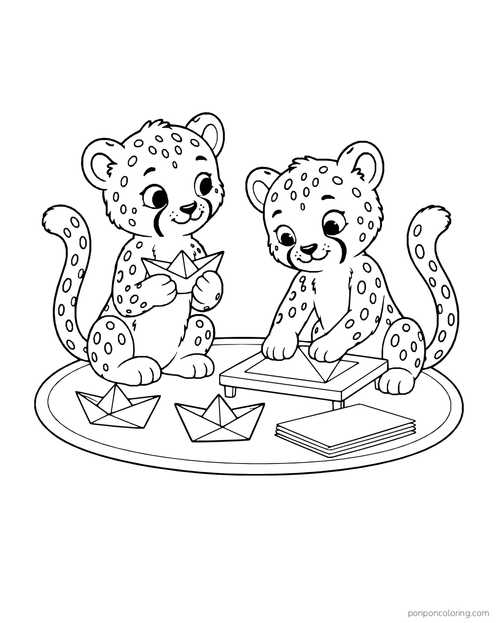 Two cheetah cubs making paper boats on an oval mat, with a low tray, two finished boats, and a stack of paper.